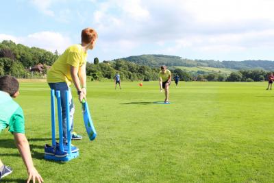 teenage boys playing cricket during sports session at uk residential summer camp