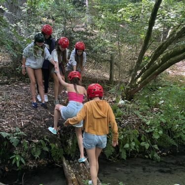 Girls helping eachother doing bridge building at a sleepaway camp